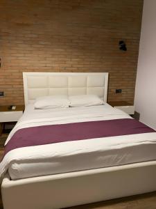 a bedroom with a white bed with a brick wall at Hotel Sidi in Tirana +47 photos