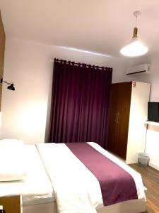 a bedroom with a bed and a purple curtain at Hotel Sidi in Tirana
