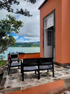 a bench sitting outside of a building next to a lake at Casa Dos Barcos Furnas in Furnas