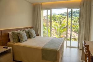 a bedroom with a large bed and a large window at Beach Hotel Paúba in São Sebastião +21 photos