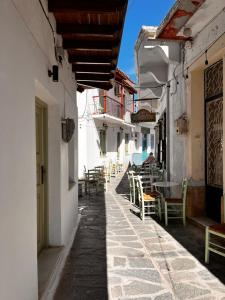 an alley with tables and chairs in a building at Happiness skopelos in Glossa