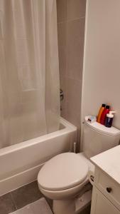 a white bathroom with a toilet and a bath tub at Luxury Heart of the city in Surrey