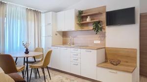 a kitchen with white cabinets and a table and a tv at Apartments Grozdana in Baška