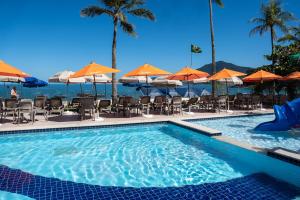 a swimming pool with tables and chairs and umbrellas at Beach Hotel Paúba in São Sebastião