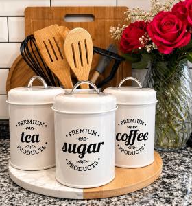 a group of three coffee cans on a counter with a vase of flowers at Garden View Suite in Gqeberha