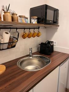 a kitchen counter with a sink and a microwave at La chambre des clefs in Ranville