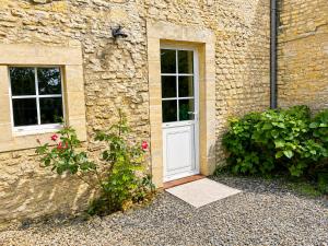 a stone building with a white door and two windows at La chambre des clefs in Ranville