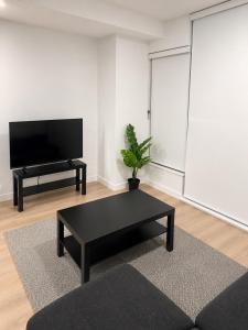 a living room with a black coffee table and a flat screen tv at Modern suite in Surrey