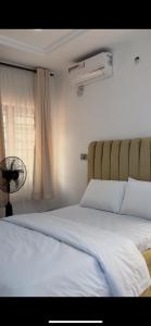 a bedroom with two beds and a window with a fan at Oak Serviced Apartment-New Bodija in Ibadan