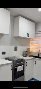 a kitchen with white cabinets and a stove top oven at Oak Serviced Apartment-New Bodija in Ibadan