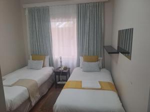 two beds in a small room with a window at Beach Hive 2 in Walvis Bay