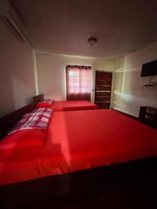 a bedroom with two red beds and a window at El Rincon De Lupe in San Carlos