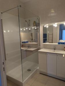 a bathroom with a glass shower and two sinks at Appartement du parc in Ambert