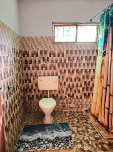 a bathroom with a toilet and a tiled wall at Mnchunge's Residence in Kikambala