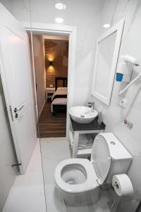 a white bathroom with a toilet and a sink at Hotel Sidi in Tirana