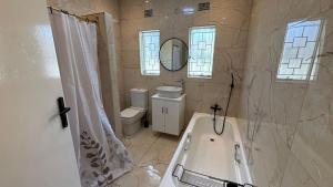 a bathroom with a tub and a toilet and a mirror at Bella Vista in Edenvale +32 photos