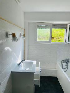 a white bathroom with a sink and a window at Chez Aurele in Villersexel
