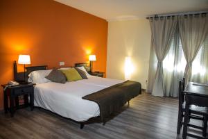 1 dormitorio con 1 cama grande y paredes de color naranja en Hotel Venta Magullo en La Lastrilla