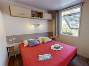 a bedroom with a red bed with a hat on it at Camping les Lauriers Roses in Fréjus +82 photos