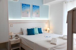 a bedroom with a white bed with blue pillows at El Greco Nei Pori in Nei Poroi