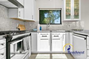 a white kitchen with white cabinets and a window at Coastal Treehouse in Aptos