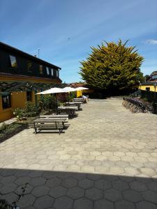 a patio with benches and umbrellas in front of a building at Albi's Sandvig Boutique Hotel in Sandvig