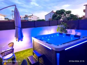 a hot tub in a backyard with an umbrella and a chair at EriZen Jacuzzi suites in Keramoti