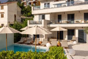 a pool with chairs and umbrellas and a building at Mamei Boutique Villa in Dobrota