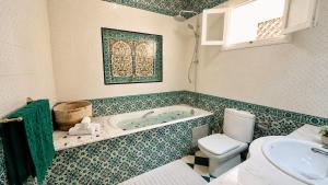 a bathroom with a tub and a toilet and a sink at Dar Joud in Gabès