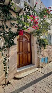 a wooden door on a building with pink flowers at Dar Joud in Gabès