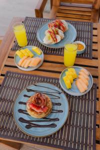 a table with plates of food and glasses of orange juice at Huku Beach Hostel Palomino in Palomino