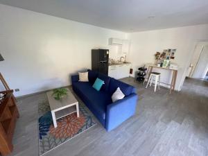a living room with a blue couch and a kitchen at Tahiti Green Lodge in Punaauia