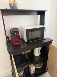 a microwave sitting on a black shelf in a kitchen at Le petit port de boucain in Port-de-Bouc