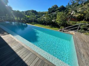 a swimming pool with blue water and a wooden deck at Tahiti Green Lodge in Punaauia