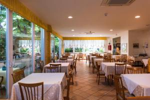 a restaurant with tables and chairs and windows at Hotel Sylvia in Lido di Camaiore