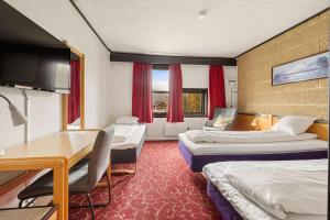 a hotel room with two beds and a desk at Ørnes Hotell in Ørnes