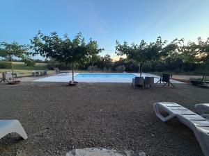 a swimming pool with benches and trees in front of it at Moto Albergue Farango FOR MOTORBIKERS ONLY - SOLO PARA MOTEROS in Benabarre