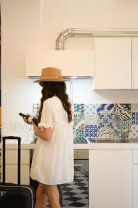 a woman wearing a hat standing in a kitchen at Ganimede Centro Storico in Sperlonga