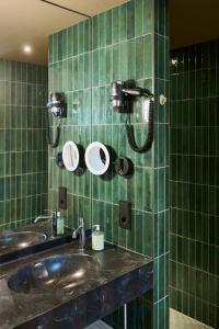 ein grün gefliestes Badezimmer mit zwei Waschbecken und Spiegeln in der Unterkunft Belsers Hotel in Nürtingen