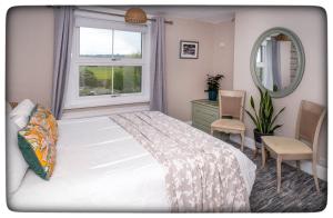 a bedroom with a bed and a window and a mirror at Britmead Guesthouse in West Bay
