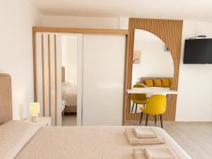 a bedroom with a mirror and a table with yellow chairs at Panorama Chill in Rafailovici