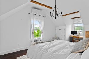 a white bedroom with a bed and a desk at Cozy Greenport Cottage in Greenport