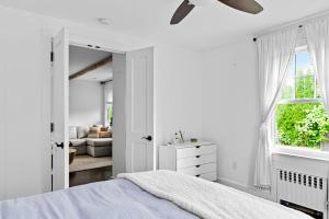 a white bedroom with a bed and a window at Cozy Greenport Cottage in Greenport +16 photos