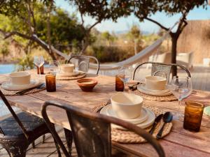 a wooden table with plates and cups and wine glasses at Finca W - Coín - Málaga - Andalucía in Coín