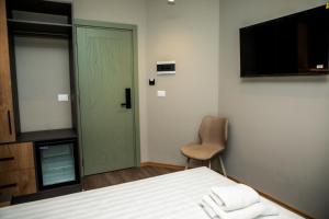 a room with a bed and a television and a chair at HOTEL CENTERPOINT Tirana in Tirana