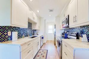 a kitchen with white cabinets and blue tiles on the wall at Tranquility on the Lake in Montgomery +33 photos