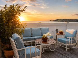 a patio with chairs and a couch and a table at Beachfront Bliss - Stay Waiheke in Onetangi