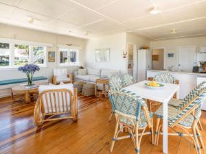 a kitchen and living room with a table and chairs at Beachfront Bliss - Stay Waiheke in Onetangi