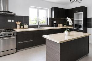 a kitchen with black cabinets and a stainless steel appliance at THE POOL LABONE in Accra