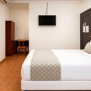 a bedroom with a bed and a television on the wall at Hotel Verona in San Pedro Sula
